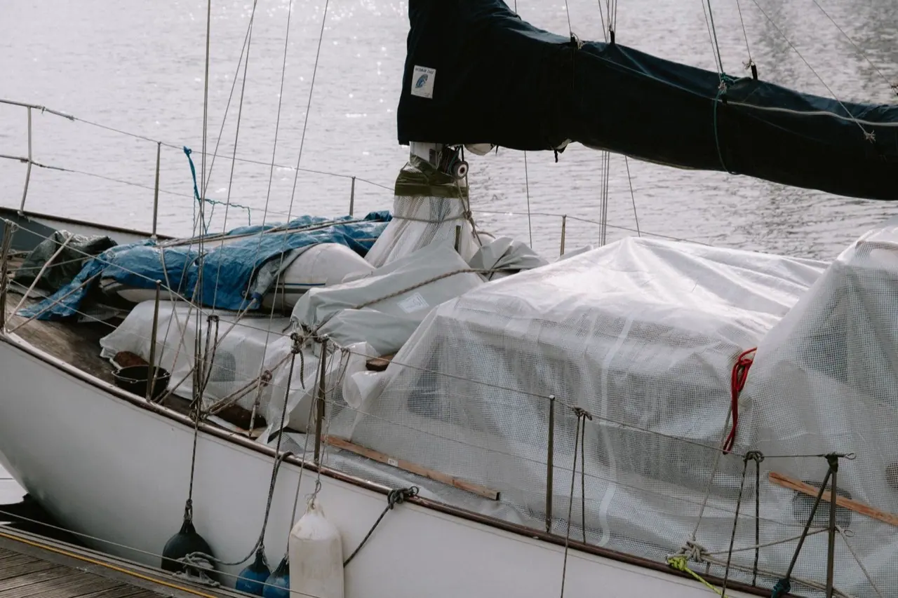 A sailboat in port with a fitted cover over the deck