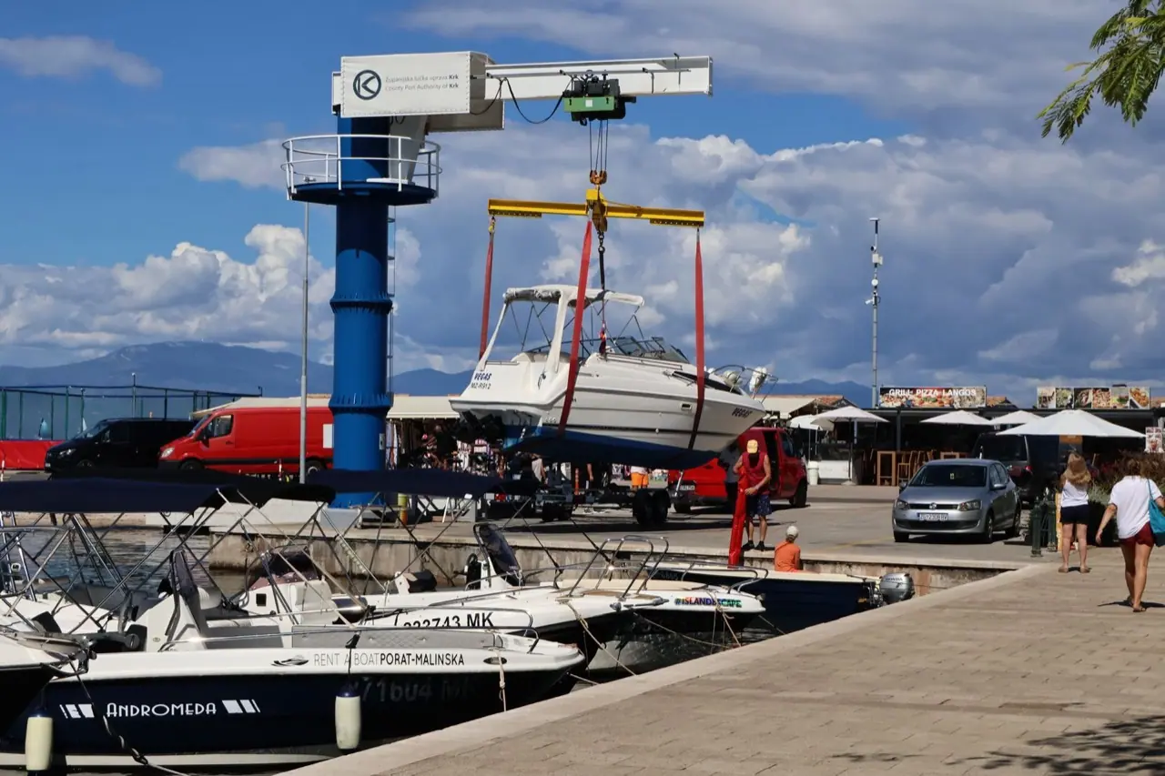 A boat hanging in the slings of a travel lift during haul-out