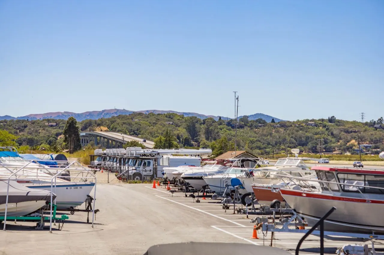 Boats and RVs parked together in a storage lot near a marina