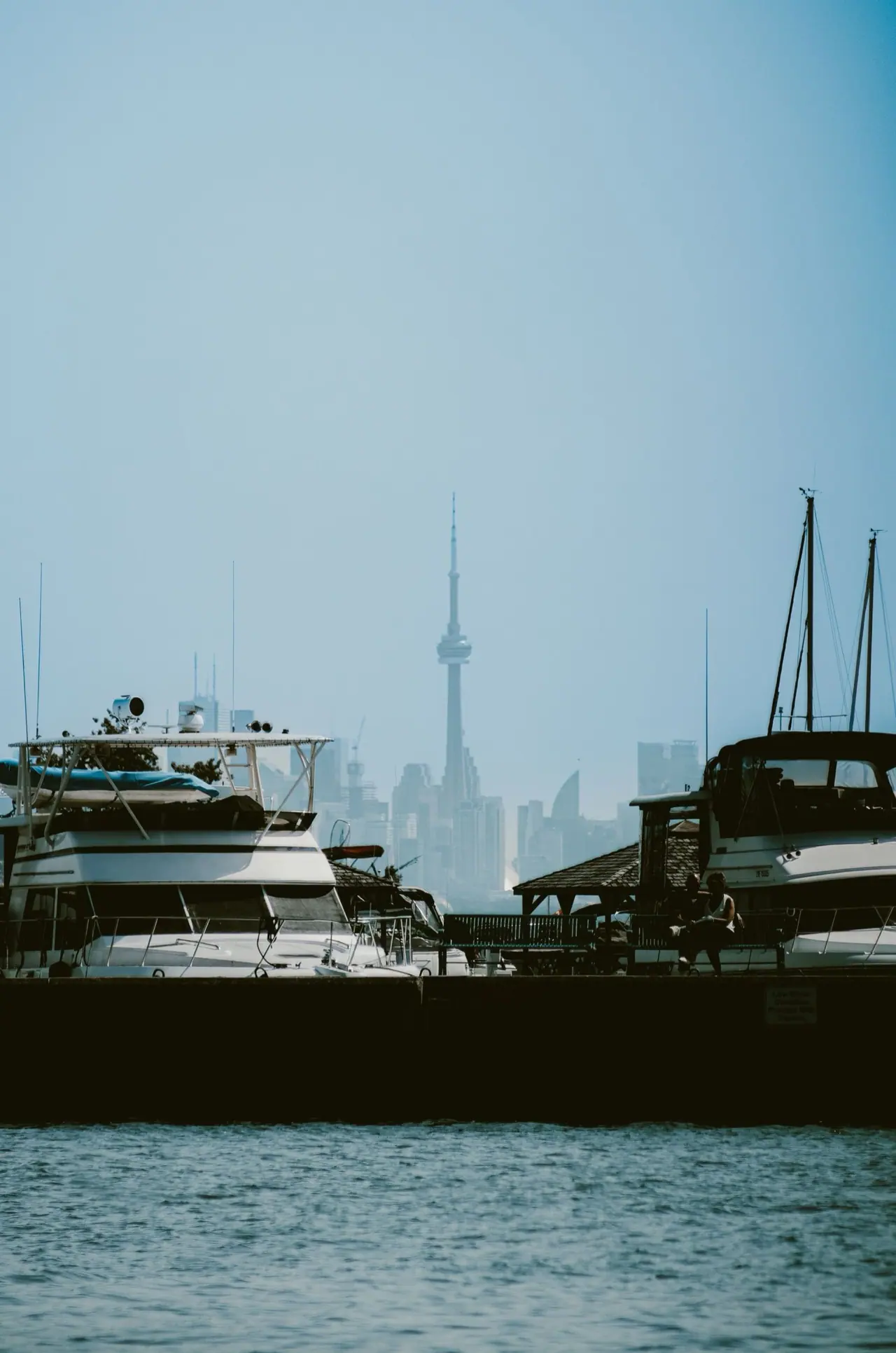 Boats docked in a Lake Ontario harbour with the Toronto skyline