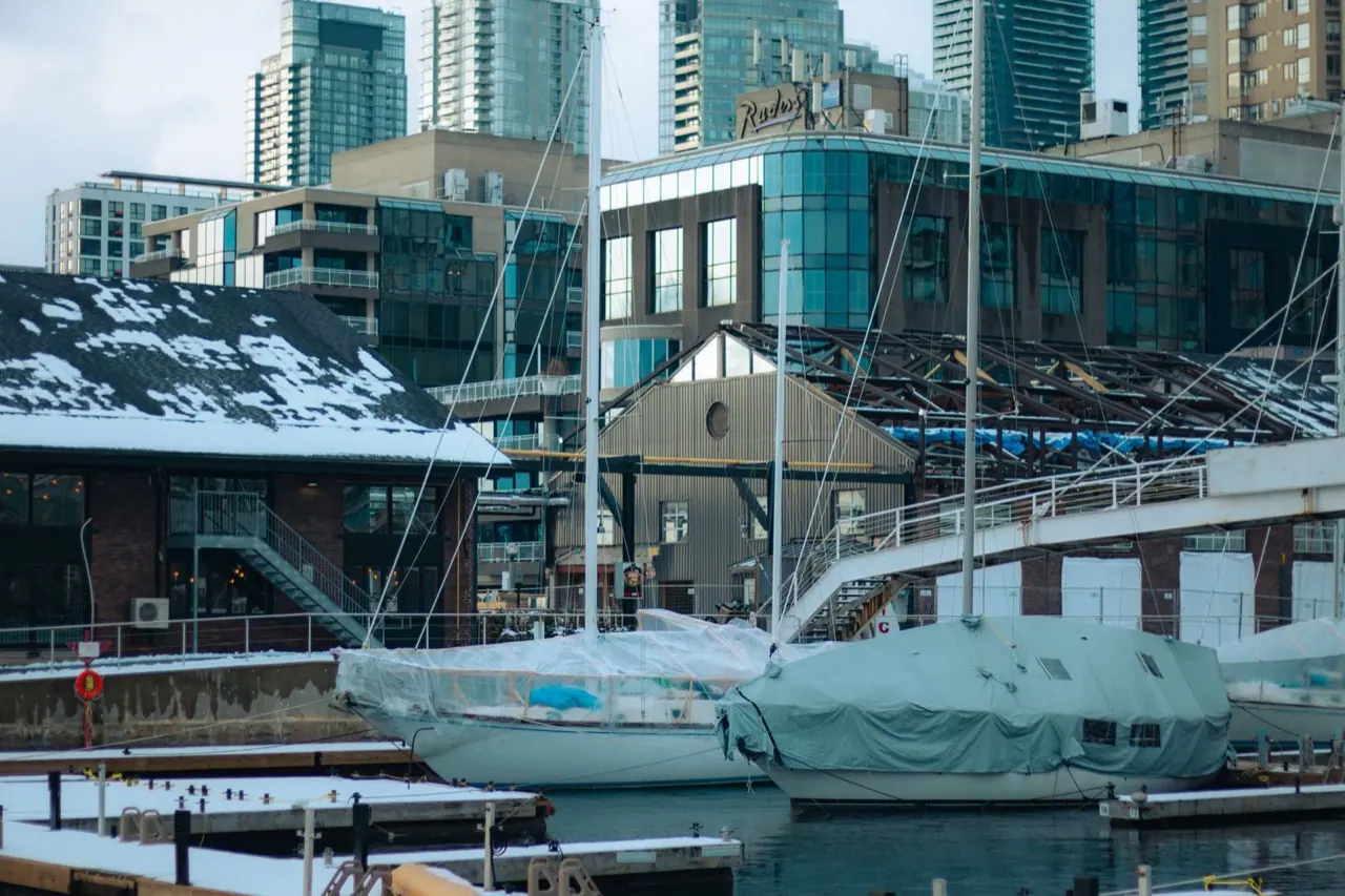 Snow-covered yachts in winter storage with the Toronto skyline behind