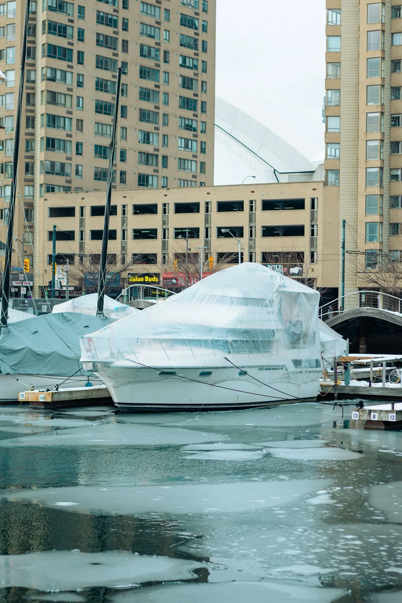 Covered yachts stored for winter beside a frozen Toronto marina